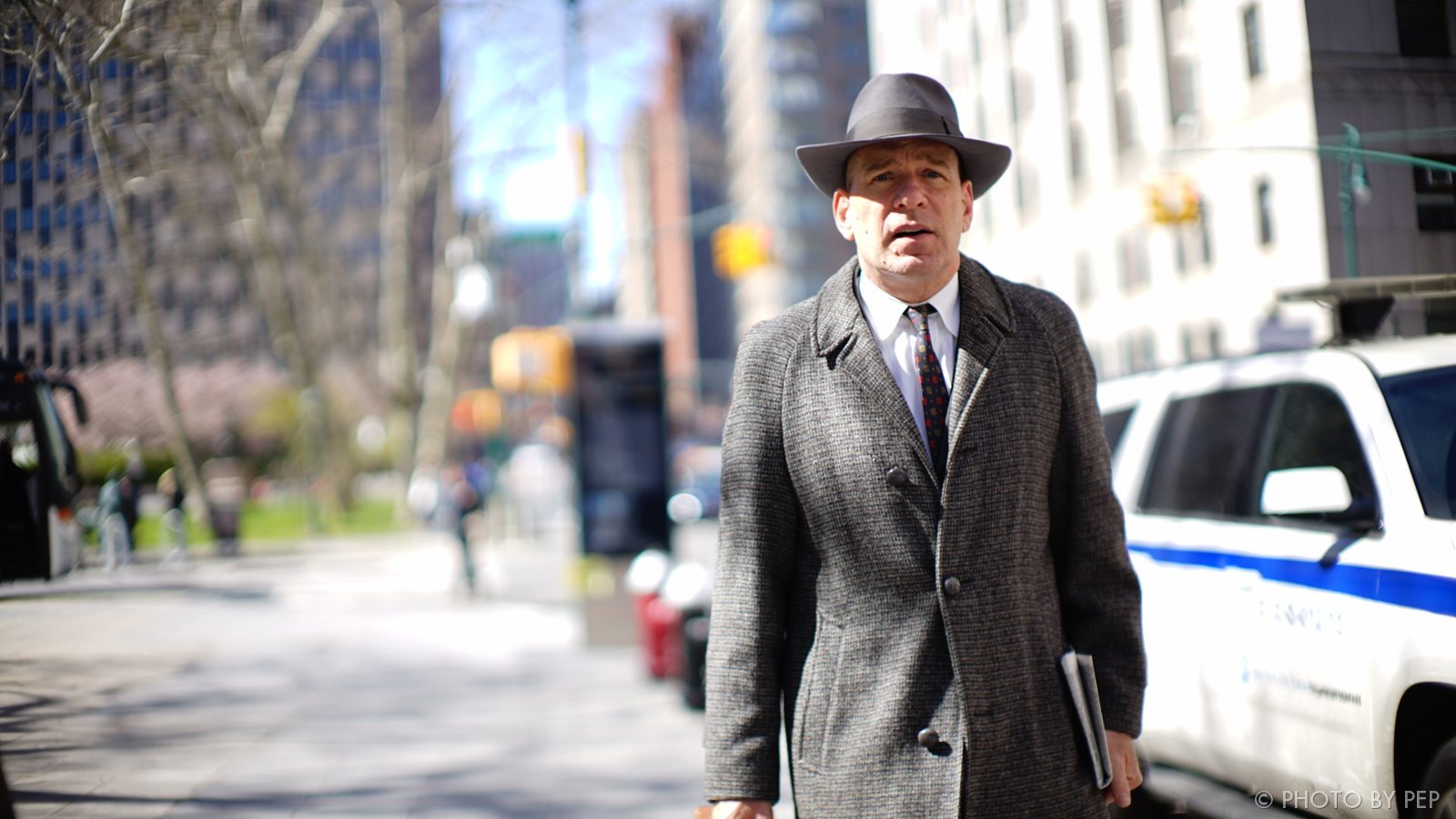 Man in fedora and overcoat on a sunny New York street